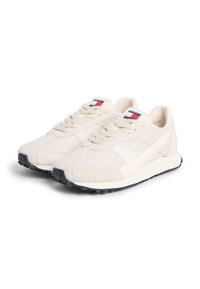 Μπεζ αθλητικά παπούτσια με υφές από δίχτυ και σουέτ, αντιθετικές λευκές και ναυτικές λεπτομέρειες, στρογγυλεμένη μύτη και επίπεδα κορδόνια.