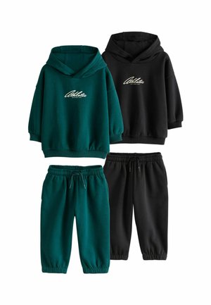 Junge mit blondem Haar und blauen Augen, der einen dunkelgrünen Hoodie mit dem Wort "Athletic" vorne trägt und zur Seite schaut.