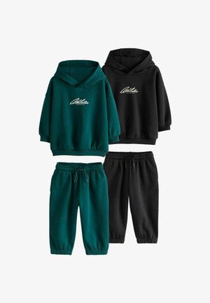 Junge mit blondem Haar und blauen Augen, der einen dunkelgrünen Hoodie mit dem Wort "Athletic" vorne trägt und zur Seite schaut.