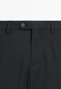 Schwarz gemusterte Hose aus strukturiertem Stoff. Verfügt über einen Knopfverschluss vorne und zwei seitliche Taschen. Elegantes kariertes Design.