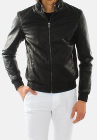 Giubbotto di pelle nera con un design elegante, chiusura con zip, polsini a coste e tasche laterali. Texture liscia e forma aderente.