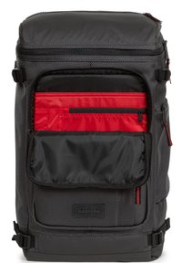 Tumma harmaa reppu, jossa on teksturoitu kangas, etupockets mustana ja punaisena, vetoketjut ja säädettävät hihnat. Mukana Eastpak-logo pohjassa.