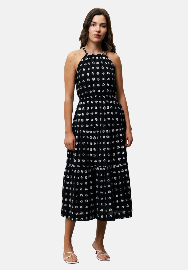 Schwarzes, ärmelloses Maxikleid mit weißem Blumenmuster, taillierten Oberteil und gestuftem Rock. Der Stoff wirkt leicht und hat eine strukturierte Oberfläche.