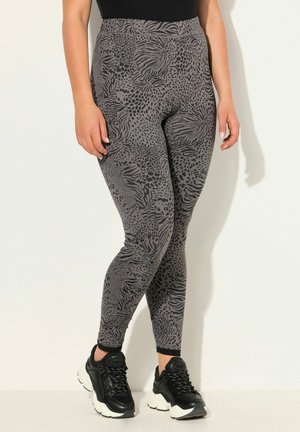 Leggings grigi con un motivo astratto a stampa animale, design a vita alta e texture morbida, abbinati a scarpe da allenamento nere.