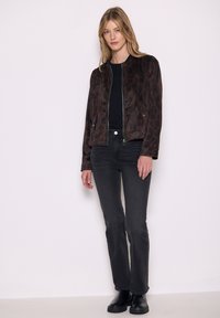 Giacca bomber con stampa leopardata marrone, t-shirt nera e jeans neri. La giacca presenta una chiusura con zip e due tasche frontali.