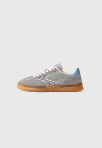 Sneaker bassi in feltro grigio e suede con lacci bianchi, dettaglio laterale glitterato, linguetta sul tallone blu e suola in gomma traslucida marrone.