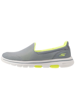 Szary sneaker slip-on z oddychającą cholewką z siateczki, neonowożółtą wyściółką, białą podeszwą oraz logo Skechers po stronie pięty.
