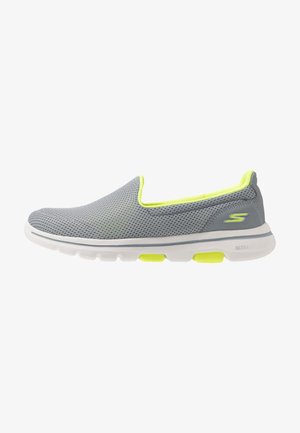 Baskets gris sans lacets avec une tige en mesh respirant, doublure jaune fluo, semelle blanche et logo Skechers sur le côté du talon.