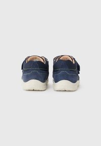Navy blue suede sneakers with a white rubber sole, featuring green stitching accents and Velcro straps for easy fastening.