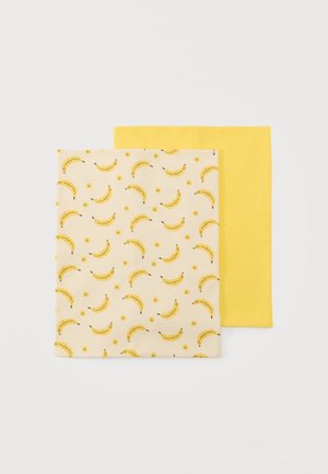 To foldede rektangulære stofstykker, et ensfarvet gult og et cremefarvet med et gentaget mønster af gule bananer.