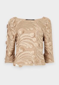 Beige transparente Bluse mit kunstvollen, farnähnlichen Stickmustern, mit Dreiviertelärmeln und geradem Halsausschnitt.