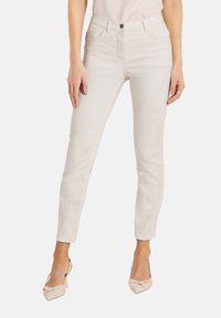 Weiße, taillierte Jeans aus strukturiertem Stoff mit Fronttaschen, einem Knopfverschluss und geradem Beinschnitt. Kombiniert mit neutralen Absätzen.