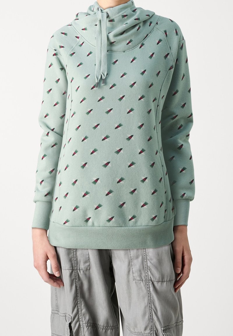 Sudadera con capucha verde menta con cuello de tortuga, con pequeños patrones repetidos de triángulos rosas y verdes. Tejido suave, puños y dobladillo acanalados.
