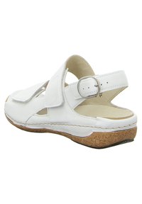 White leather sandals with adjustable buckle, cork sole, open heel, and cut-out details for ventilation. Smooth texture and lightweight design.