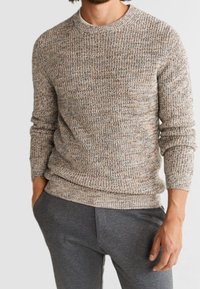 Strickpullover mit Struktur in neutraler Farbpalette, mit Rundhalsausschnitt und langen Ärmeln, kombiniert mit grauen Hose.