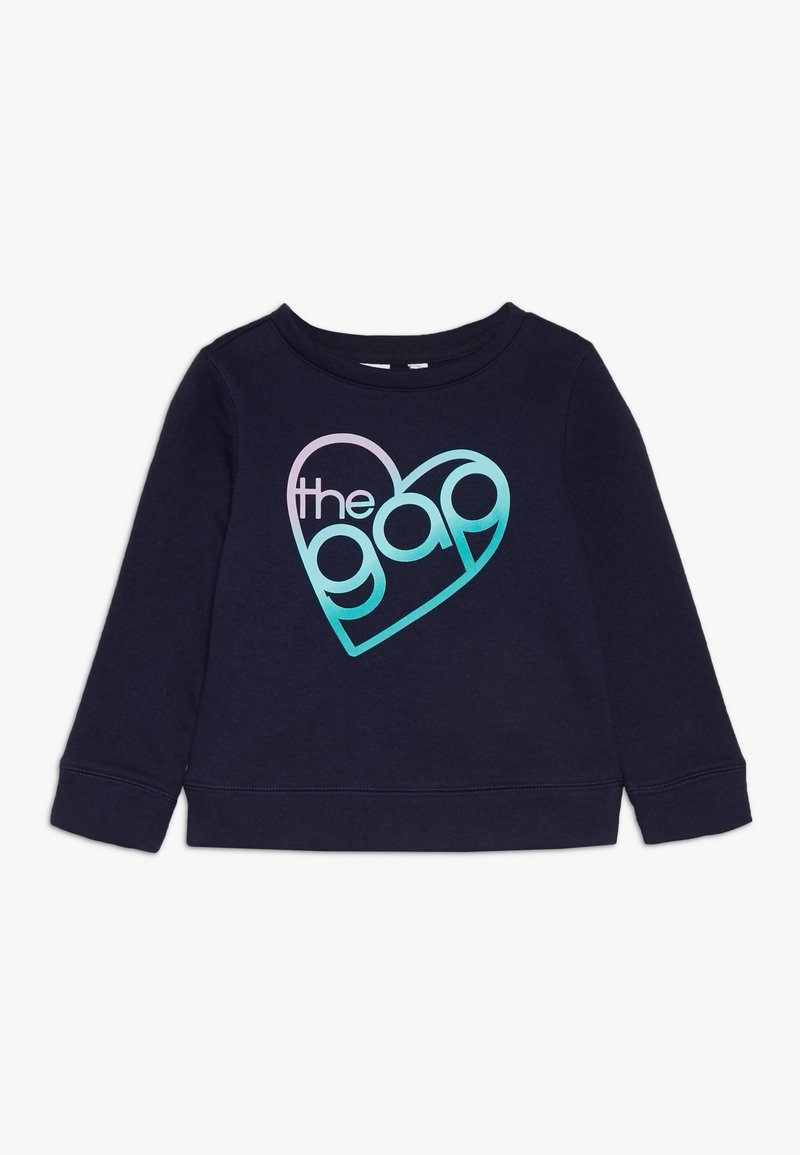 Chemise à manches longues bleu marine avec un motif cœur en dégradé contenant le mot « the gap » en lettres minuscules à l'avant.