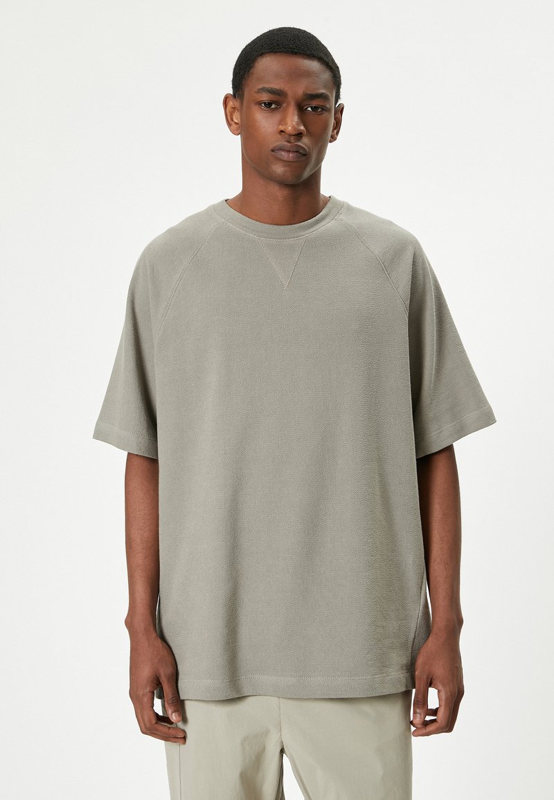Grå, struktureret oversized t-shirt med korte ærmer, en rund halsudskæring og ribbede detaljer. Glat stof med lige kant.