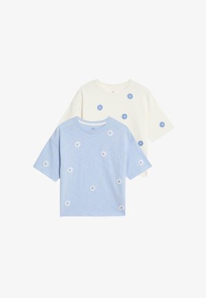 Dos camisetas de manga corta: una azul con bordado floral blanco, y una crema con acentos florales similares, hechas de una tela suave.
