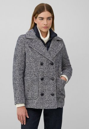 Manteau croisé en chevrons, avec des tons bleu marine et gris, de grands boutons noirs et un col en tricot texturé.