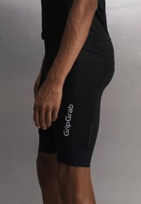 Person som har på seg svarte GripGrab sykkelshorts står på siden mot en ensfarget grå bakgrunn.