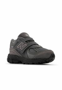 Sneaker atletica grigia con tomaia in rete e suede, cinturino in velcro, colletto imbottito e suola in gomma testurizzata per una migliore aderenza. Caratterizzato dal marchio "N" prominente.
