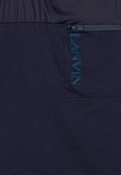 Marinefarbener Pullover mit einem leichten Oberteil, einem strukturierten Unterteil und einer Reißverschlusstasche mit einem kontrastierenden türkisfarbenen "LANVIN"-Logo.