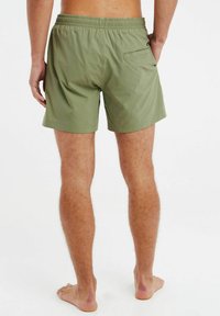 Groene zwembroek met een elastische tailleband, korte lengte, achterzak en een gladde textuur. Eenvoudig ontwerp zonder aanvullende patronen.