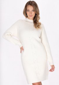 Abito maglione avorio con collo alto, maniche lunghe, texture a coste e decorazioni in perle lungo la parte frontale.
