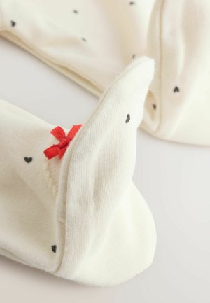 Kelių aukščio baltos kojinės su juodais širdžių raštais, papildytos raudonu kaspinu. Minkšta tekstūra, gysloti rankovės ir sulankstyti viršai patogumui.