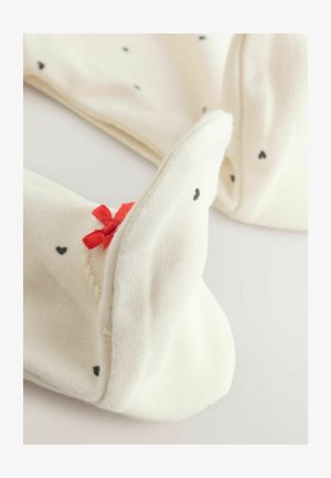 Kelių aukščio baltos kojinės su juodais širdžių raštais, papildytos raudonu kaspinu. Minkšta tekstūra, gysloti rankovės ir sulankstyti viršai patogumui.