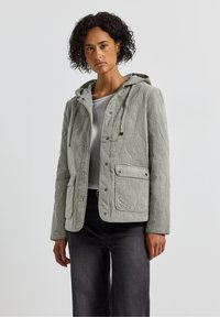 Light grey, quilted jacket with a hood, featuring snap buttons and two front pockets. Made of textured fabric, designed for casual wear.