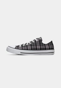 Sneaker in tela a quadri nera e rosa con punta in gomma bianca, sistema di allacciatura e suola bianca con strisce nere. Design a taglio basso.