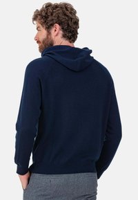 Sweat à capuche bleu marine en tissu doux et texturé. Comprend une poche kangourou à l'avant et des poignets côtelés. Lavable en machine, coupe décontractée.
