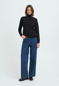 Schwarzer Rollkragenpullover mit langen Ärmeln, kombiniert mit hochtaillierten, weit geschnittenen blauen Jeans. Glatte Textur; schlichtes Design; keine Muster.