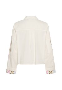 Gekürztes weißes Baumwollhemd mit langen Ärmeln und farbenfrohen Stickereien an den Manschetten. Einfacher Kragen und Rückenteil mit Schulterpasse.