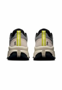 Leichte Sportschuhe mit einem grauen und schwarzen Obermaterial, das einen auffälligen gelben Strich, eine strukturierte Fersenstütze und eine gepolsterte Sohle aufweist.