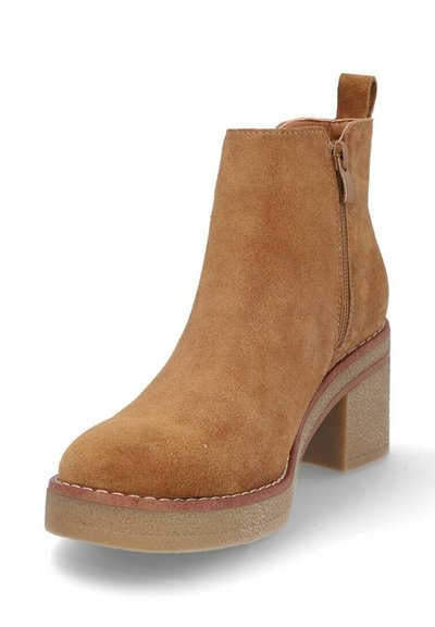 Botín de ante en color camel con punta redonda, cremallera lateral y tacón grueso. Suela texturizada con un detalle de costura en contraste.