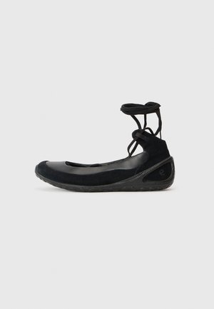 Des ballerines noires en suède, avec une semelle en caoutchouc et des lacets entrecroisés. Présentant un bout rond et une accent latéral texturé.