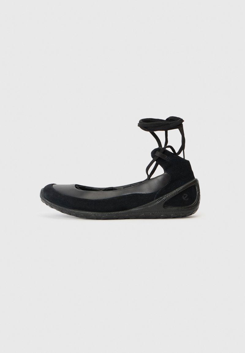 Des ballerines noires en suède, avec une semelle en caoutchouc et des lacets entrecroisés. Présentant un bout rond et une accent latéral texturé.