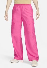 Rosa cargo-byxor med elastisk midja, två sidofickor och ett Nike-logotyp. Har en lös, bred ben-design och en slät, glänsande textur.