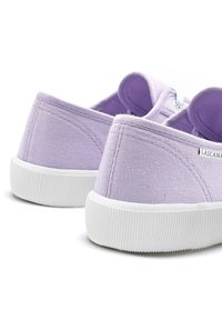 Le sneakers viola in canvas presentano un design a scarpa bassa, suole in gomma bianca e dettagli testurizzati. I lacci sono visibili sul davanti.