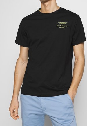 Sort bomulds-T-shirt med Aston Martin Racing-logo i gult på venstre bryst. Rund hals og korte ærmer med en afslappet pasform.