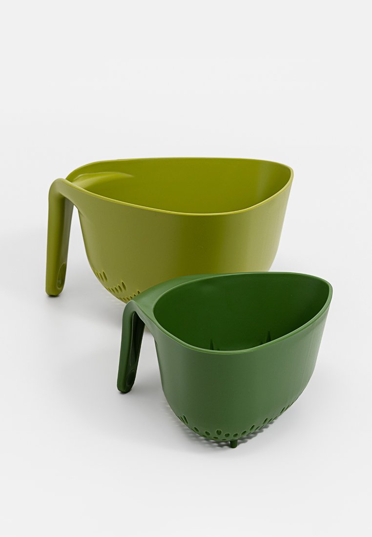 Dos coladores de plástico en tonos verdes, uno más grande y otro más pequeño, con un asa y orificios de drenaje en la base.