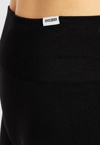 Leggings noirs taille haute avec une texture côtelée. Présentent une petite étiquette blanche "SMILODOX" sur la taille. Finition en tissu lisse.