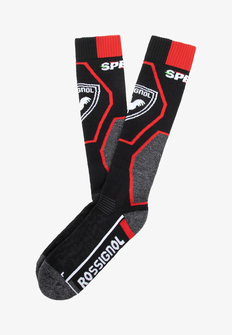 Calcetines de esquí negros con acentos rojos, que presentan un diseño texturizado, logotipos en blanco y una puntera reforzada. Parte superior acanalada para un ajuste seguro.