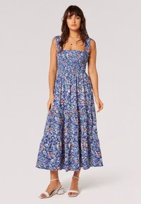 Floral-Maxikleid mit gerafftem Oberteil, breiten Trägern und einem gestuften Rock in Blau-, Orange- und Grüntönen sowie einer weichen Stoffstruktur.
