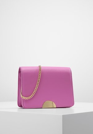 Fialová kožená kabelka s pozlaceným půlměsíčkovým zapínáním a zlatým řetízkovým popruhem, vystavená na bílém podstavci proti jednoduchému pozadí.