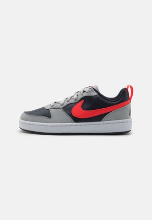 Lav-tops sneaker med grå og sorte paneler, rød Nike-swoosh og hælfane, hvid sål med sort slidbane og grå snørebånd.