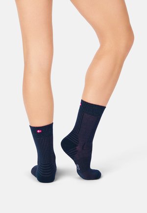 Marineblaue Socken mit Crew-Schnitt, ausgestattet mit einem strukturierten Strickmuster und einem gerippten Bündchen. Sie haben ein kleines Logo mit rosa Akzenten an der Ferse und dem Bündchen.