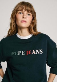 Mörkgrön sweatshirt med broderad "PEPE JEANS" i olika färger. Rund halsringning med ribbade mudd. Avslappnad passform. Mjuk textur.